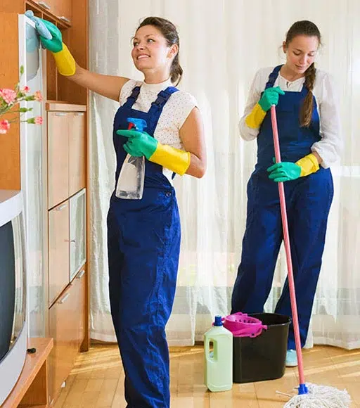 Two women cleaning the floor and furniture